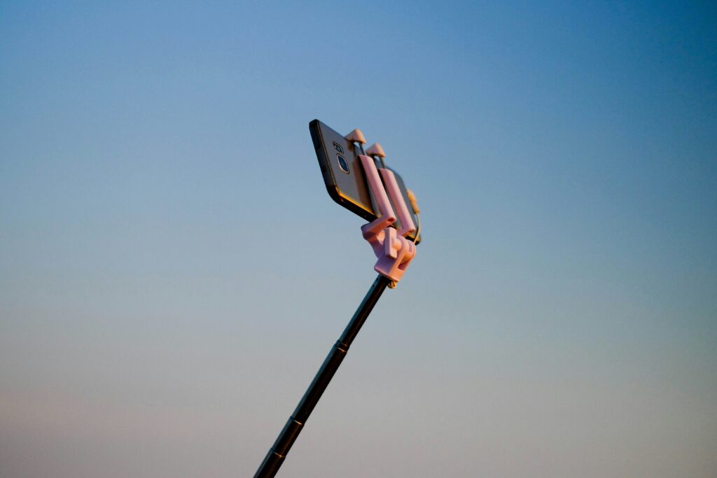 Influencer selfie-stick with phone against blue sky